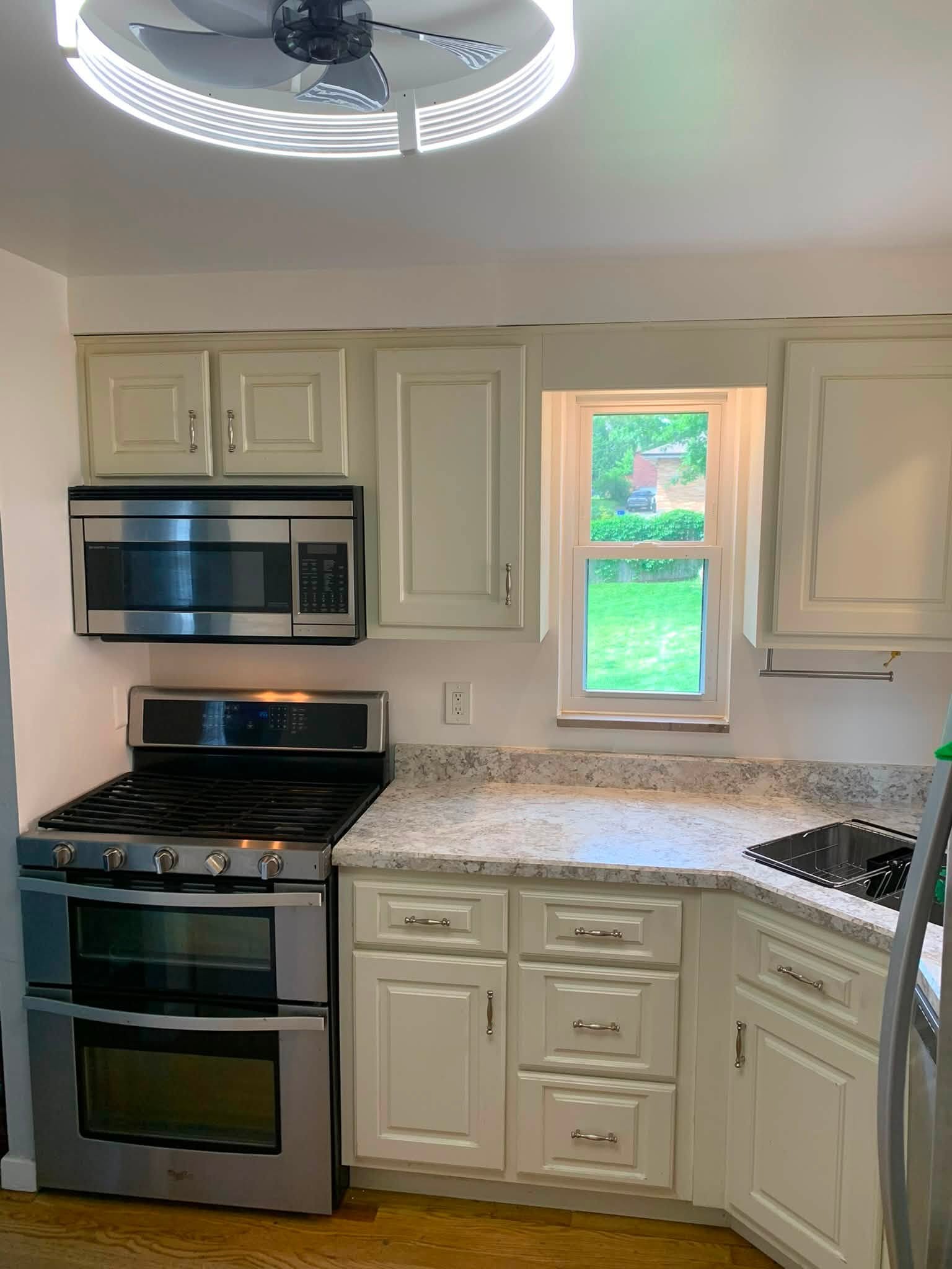 A repainted kitchen with cream cabinets and stainless appliances